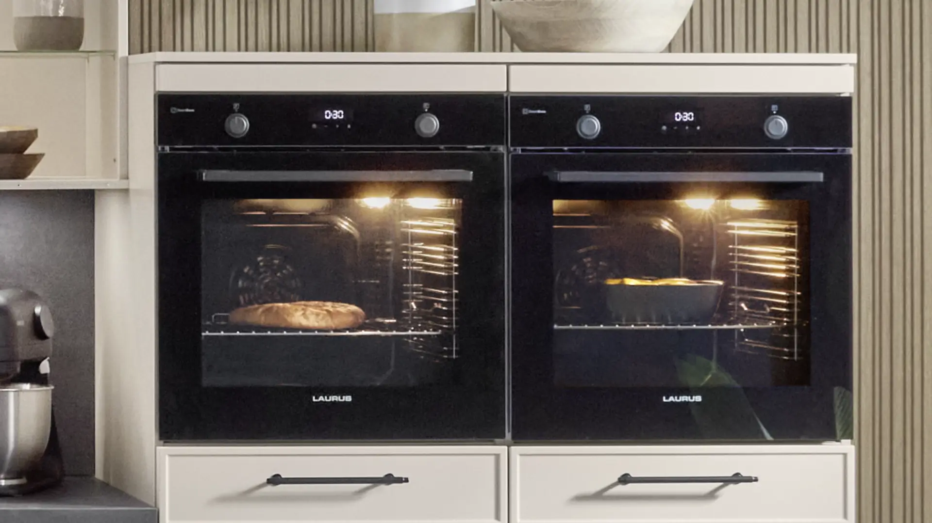 Zwei in einen Einbauschrank integrierte schwarze Einbaubacköfen der Marke Laurus, beide mit beleuchtetem Innenraum, brot und gebackene Speisen sichtbar.